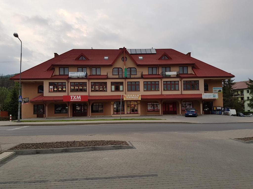 a large building with a red roof on a street at Gościniec Ustrzycki in Ustrzyki Dolne