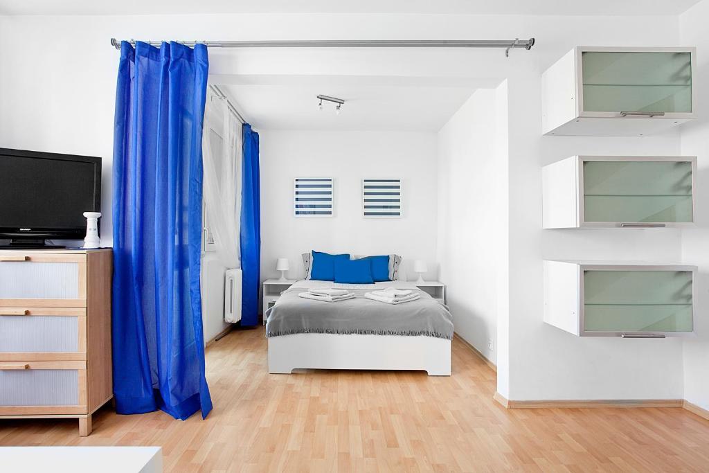 グディニャにあるApartament Morskiの白いベッドルーム(青いカーテン、ベッド1台付)