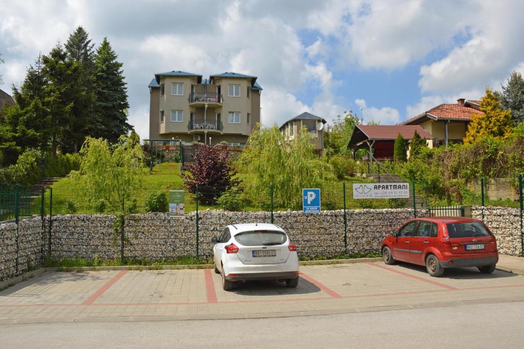 dos autos estacionados en un estacionamiento frente a un edificio en Apartments Vila Vrdnik en Vrdnik