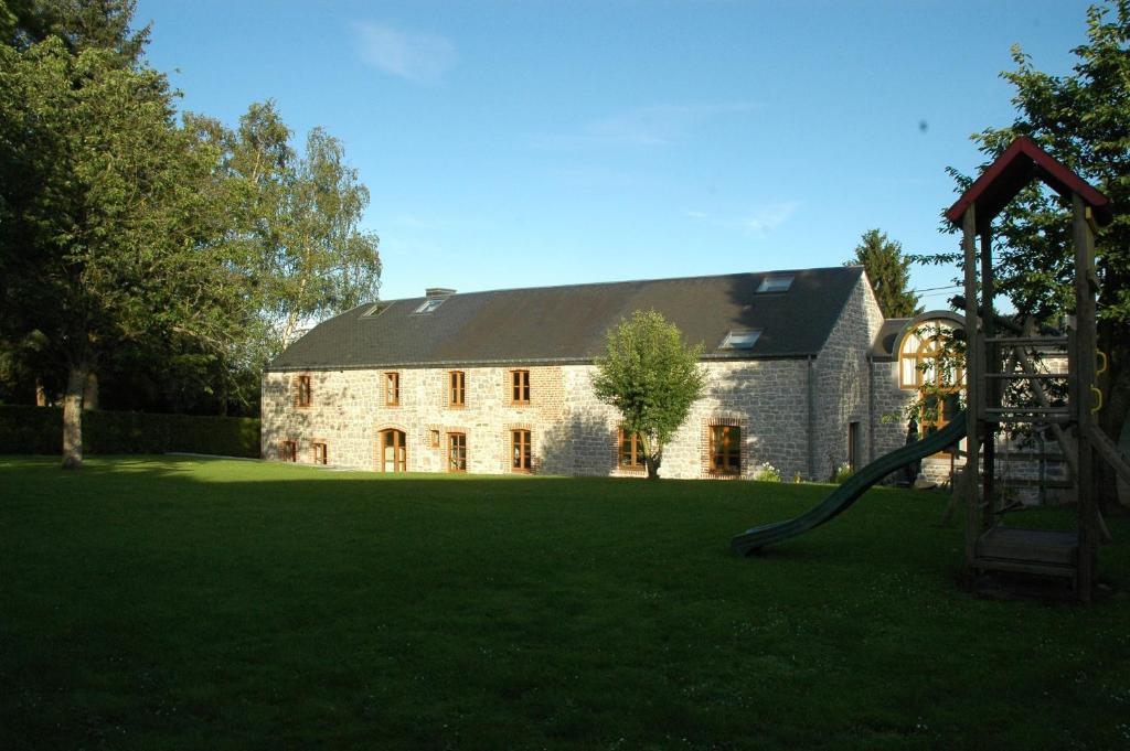 un grande edificio in pietra con parco giochi in un cortile di Gïte de l'EHM a Custinne