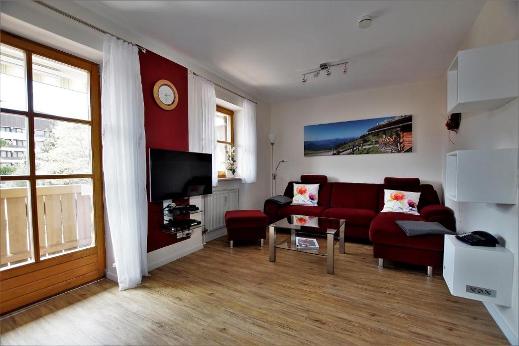 a living room with a red couch and a table at Ferienwohnung Benediktenwand in Lenggries