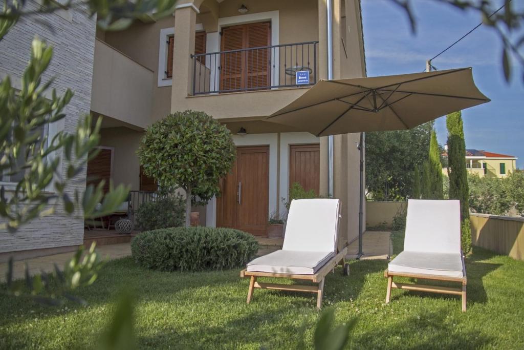 two chairs and an umbrella in front of a house at Apartment Varga in Zadar