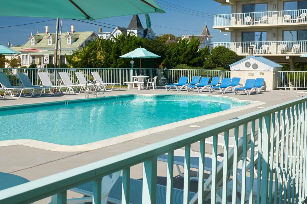 a swimming pool with lounge chairs and umbrellas on a balcony at Sea Crest Inn in Cape May