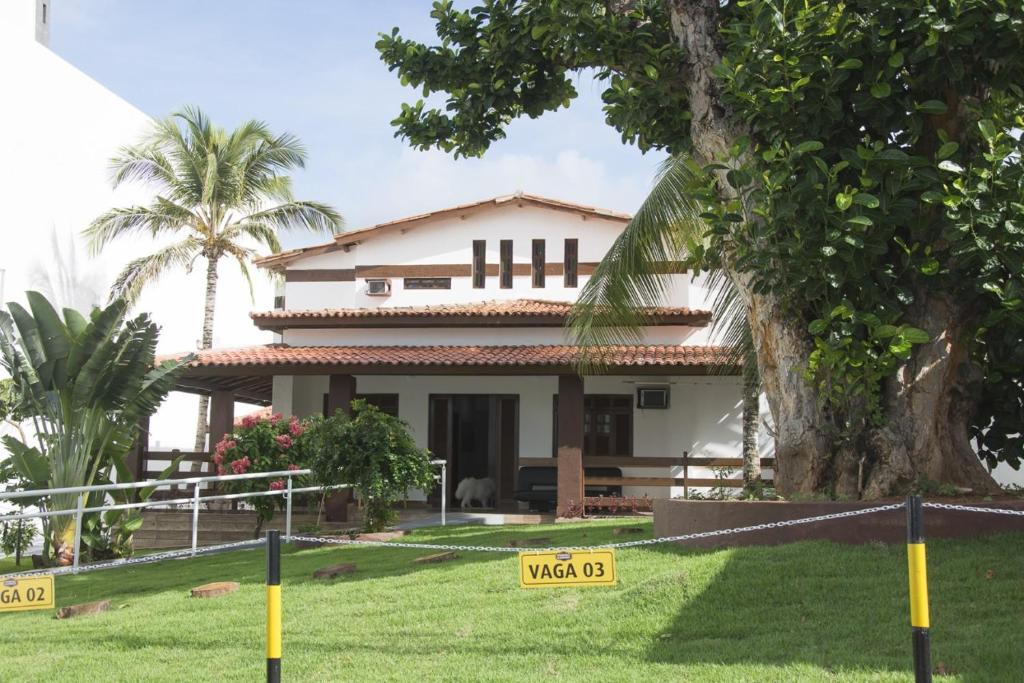 uma casa com uma árvore em frente em Pousada Eldorado em Lauro de Freitas