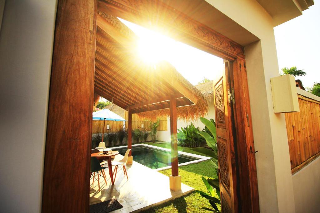 an open door to a patio with a table and a pool at Villa Saia in Gili Air