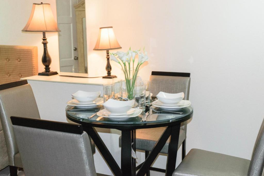 a dining room table with chairs and a table with a lamp at Glynver Apartments in Christ Church