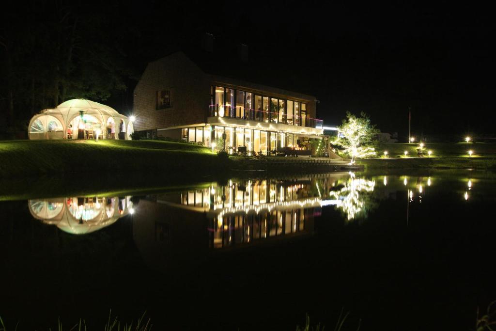 a house at night with a reflection in the water at Kernavės SPA Pajauta in Kernavė