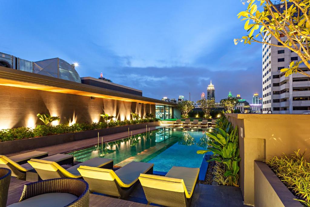a hotel pool with chairs and a building at Best Western Premier Sukhumvit in Bangkok