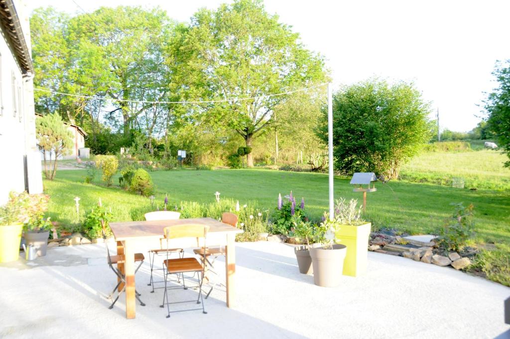 a patio with a table and chairs and a garden at Le champ Bagnolet in Voussac