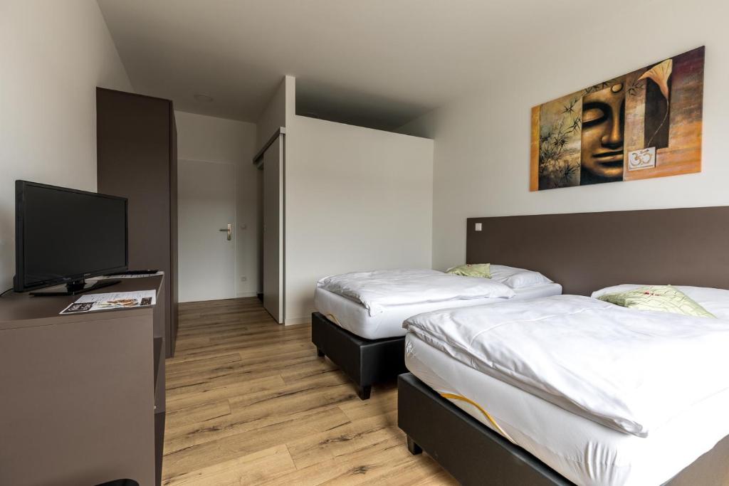 a room with two beds and a flat screen tv at Wein4tler-Motel in Gänserndorf