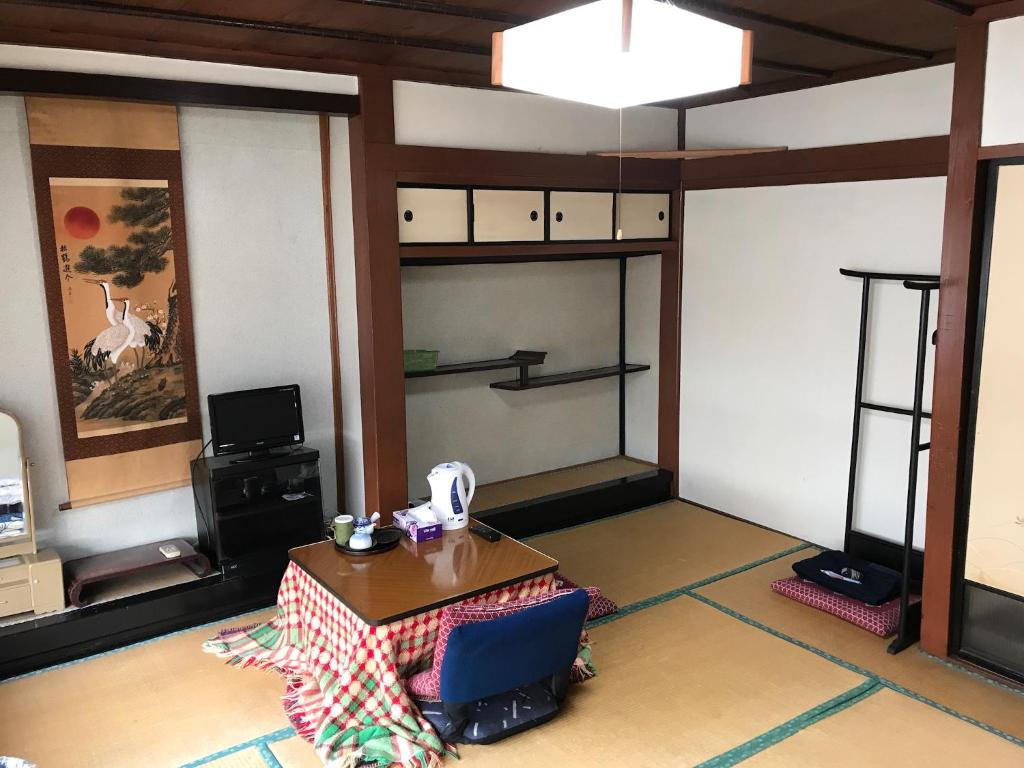 uma sala de estar com uma mesa e uma televisão em Niko Ryokan em Aizuwakamatsu