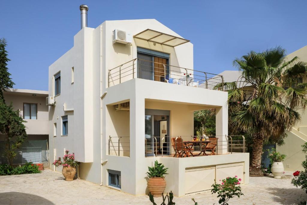 a white house with a balcony and palm trees at Villa Giannis in Almyrida