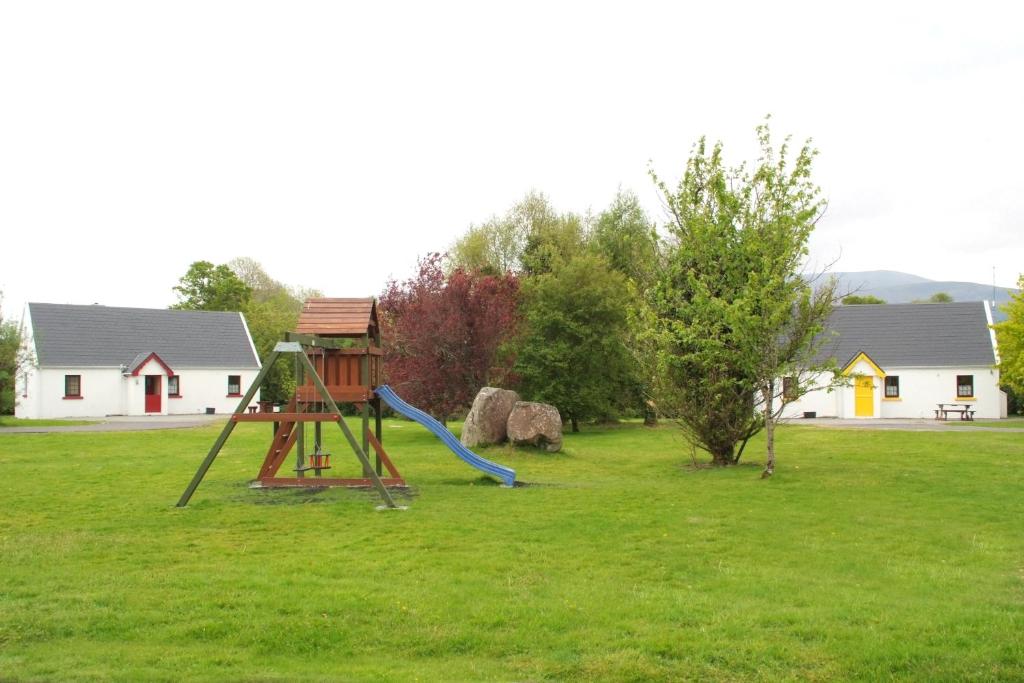 un parque infantil con un tobogán en el césped en Killarney Lakeland Cottages, en Killarney