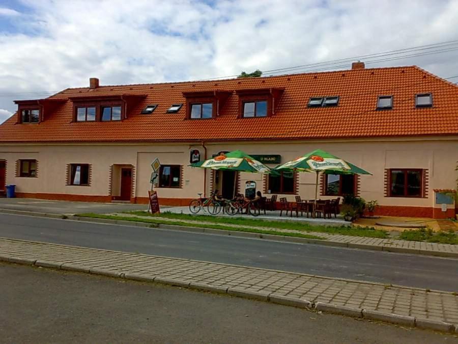 a building with tables and umbrellas in front of it at Penzion U Hladů in Úlice