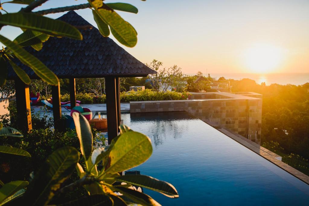 een zwembad met een prieel en de zonsondergang bij AYANA Residences Luxury Apartment in Jimbaran