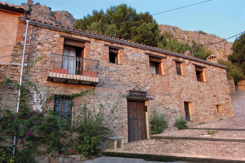 an old brick building with a door and a balcony at La Jara De Las Villuercas in Cabañas del Castillo