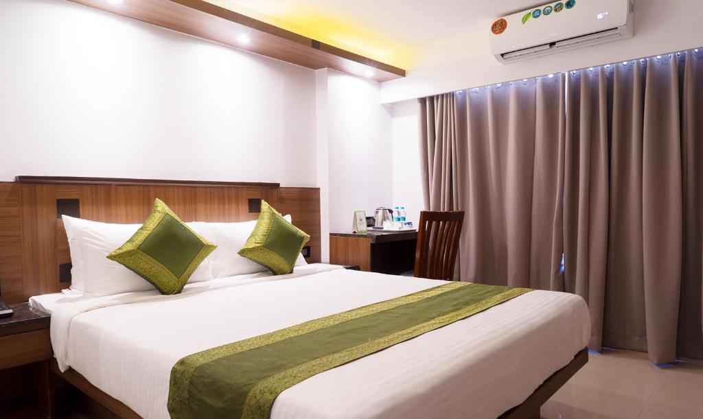 een slaapkamer met een groot wit bed met groene kussens bij Treebo Trend Olive Inn in Mumbai