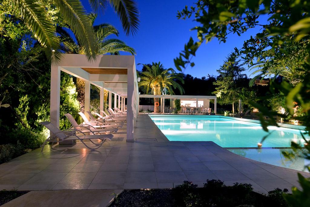 a swimming pool with lounge chairs next to a house at TRYP by Wyndham Corfu Dassia in Dassia