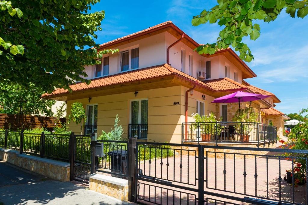 une maison avec une clôture et un parasol dans l'établissement Andi Apartman, à Hévíz