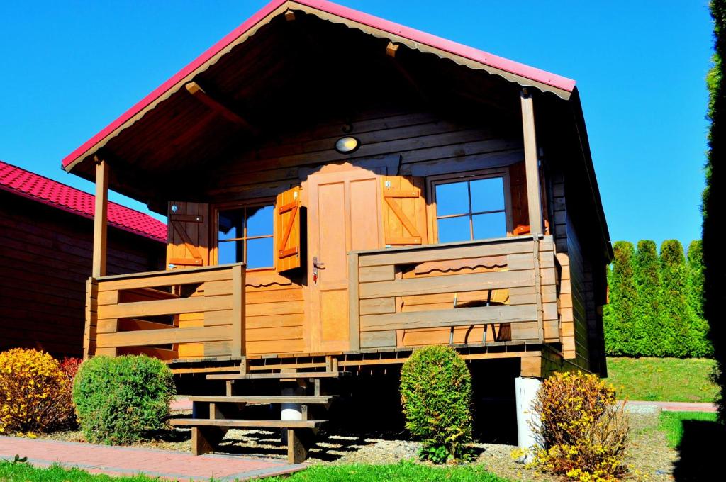 a wooden cabin with a red roof at Domki Olina in Polańczyk