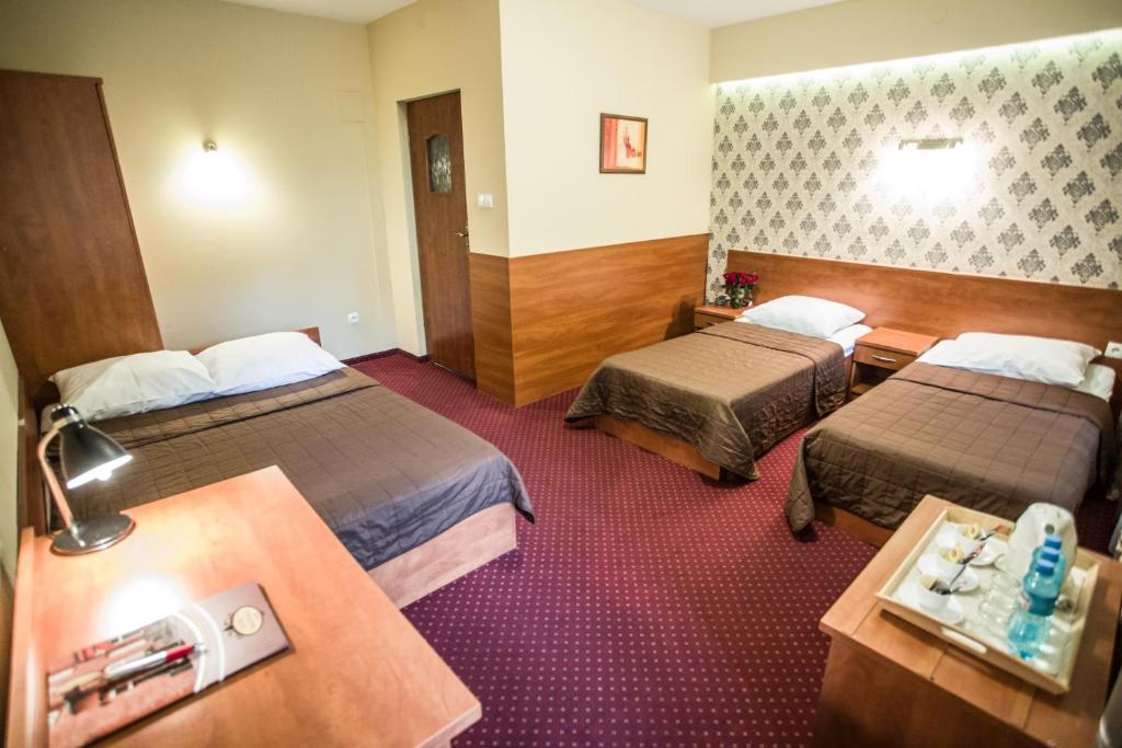 a hotel room with two beds and a table at Hotel Maksymilian in Krakow