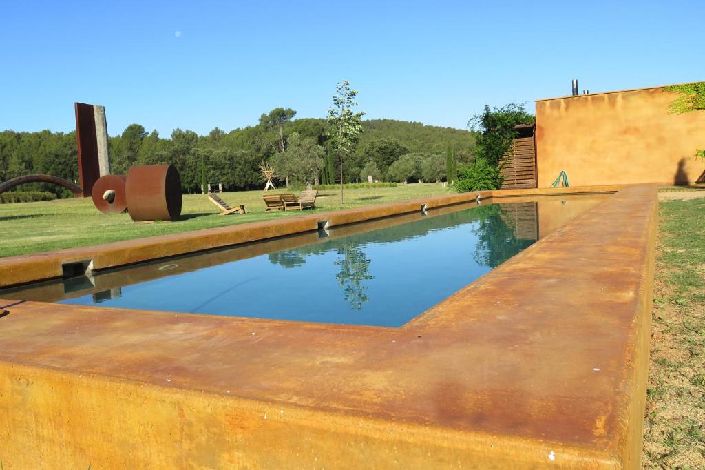 una vieja piscina oxidada en un campo con un edificio en Hotel Fundació L'Olivar, en Ventalló