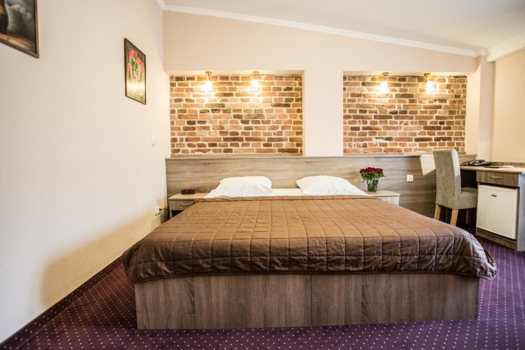 a bedroom with a bed and a brick wall at Hotel Maksymilian in Krakow