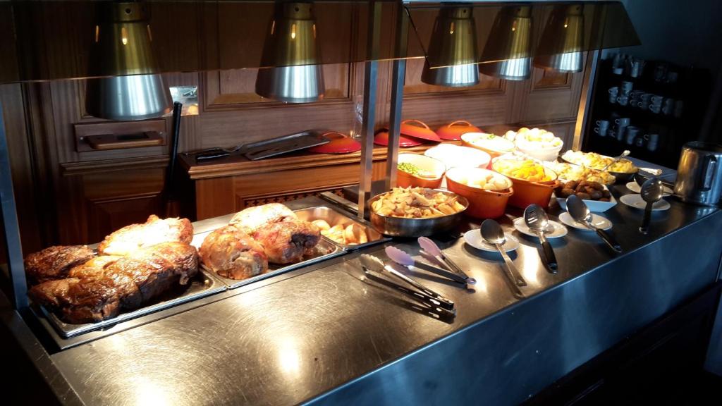 una línea de buffet con carne y otros alimentos en un restaurante en Somerfield Lodge, en Swansea