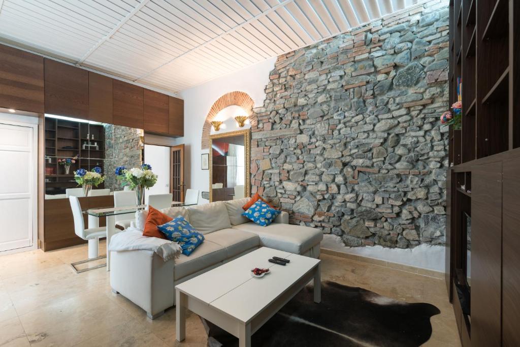 sala de estar con pared de piedra y sofá en Roommo San Iacopino, en Florencia
