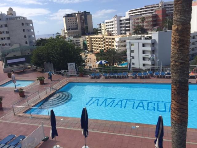 a large swimming pool in a city with buildings at Apartamentos Tamaragua in Playa del Ingles
