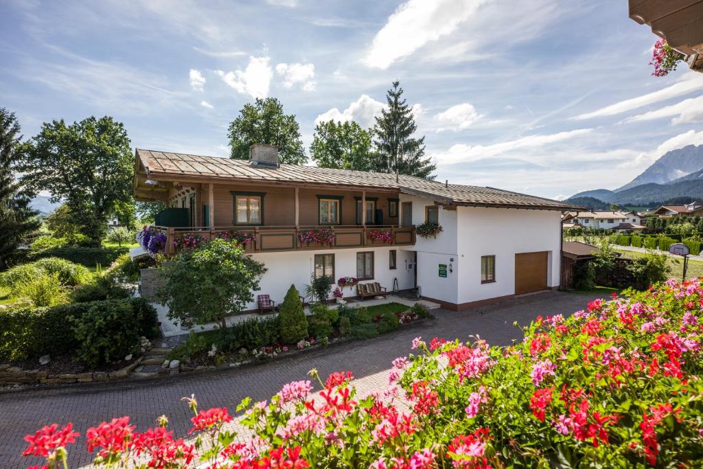 a house with flowers in front of it at Pension Garni Appartement Ortner in Sankt Johann in Tirol