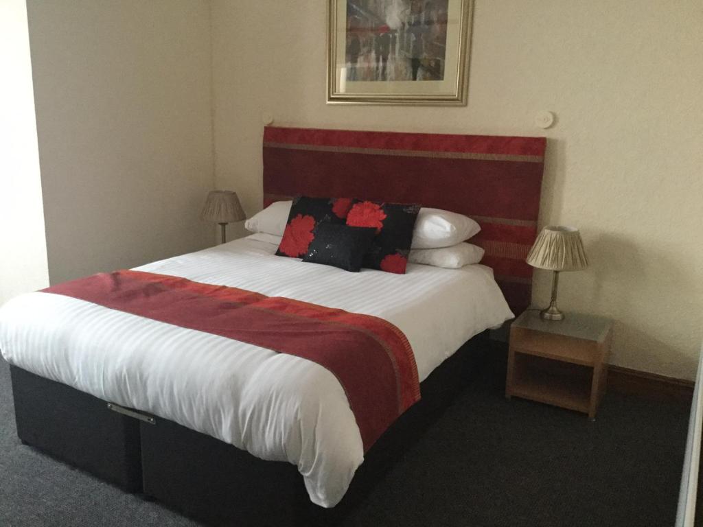 a bedroom with a large bed with a red and white blanket at Woodlands Guest House in Liverpool