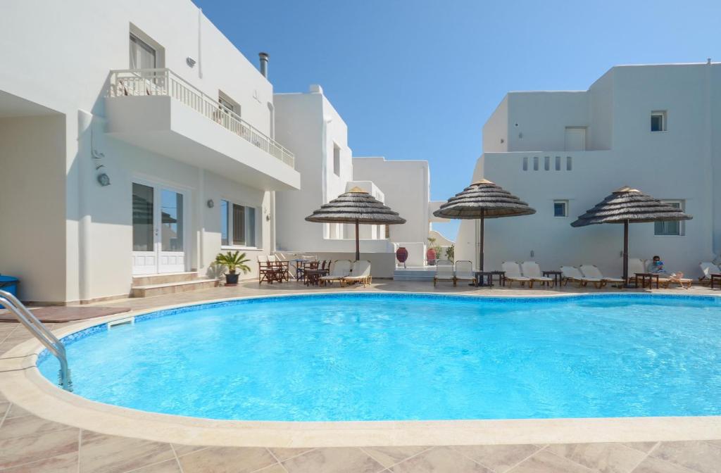 einen Pool mit Stühlen und Sonnenschirmen neben einem Gebäude in der Unterkunft Villa Adriana Hotel in Agios Prokopios