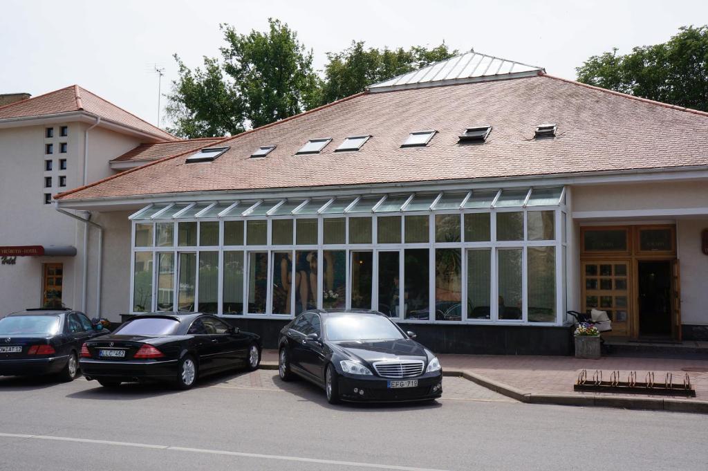 three cars parked in a parking lot in front of a building at Du Broliai Hotel in Palanga