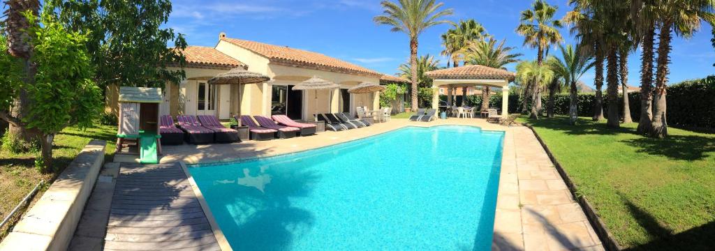 - une piscine en face d'une maison avec des palmiers dans l'établissement Luxueuse Villa Récente à Saint Raphaël de Plain Pied, à Saint-Raphaël