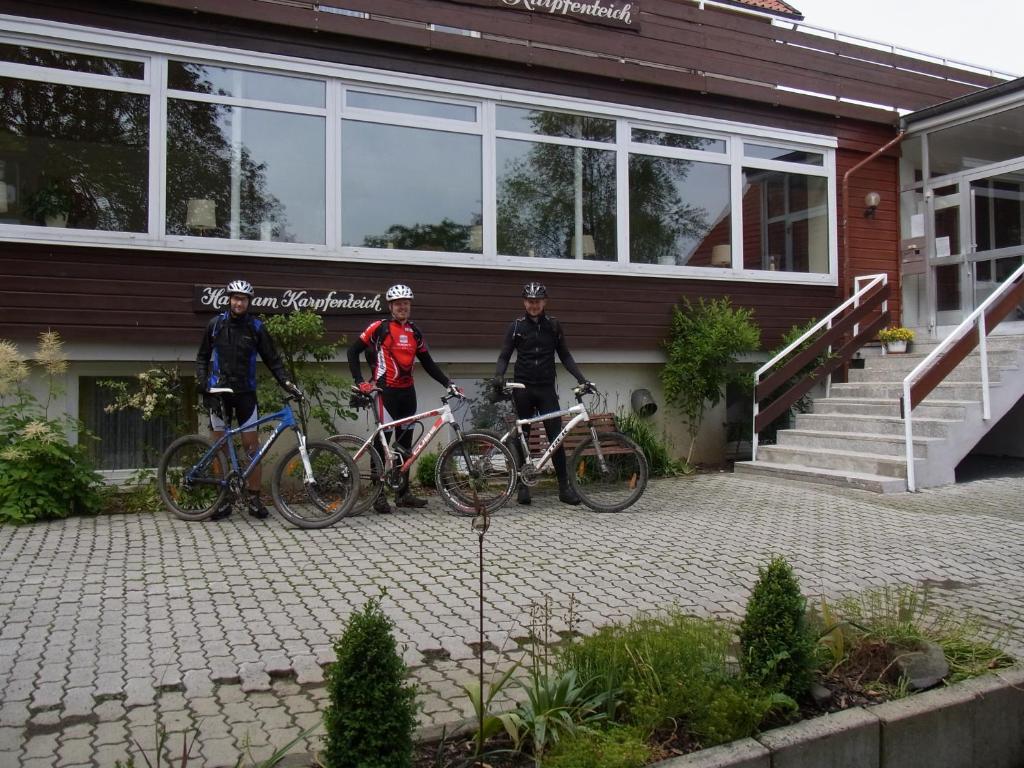 tre persone in piedi con le loro biciclette di fronte a un edificio di Haus am Karpfenteich a Hahnenklee-Bockswiese