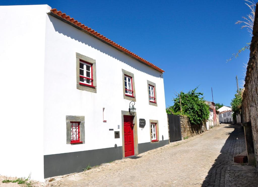 um edifcio branco com uma porta vermelha numa rua em Casa dos Hospitalrios em Alvaro