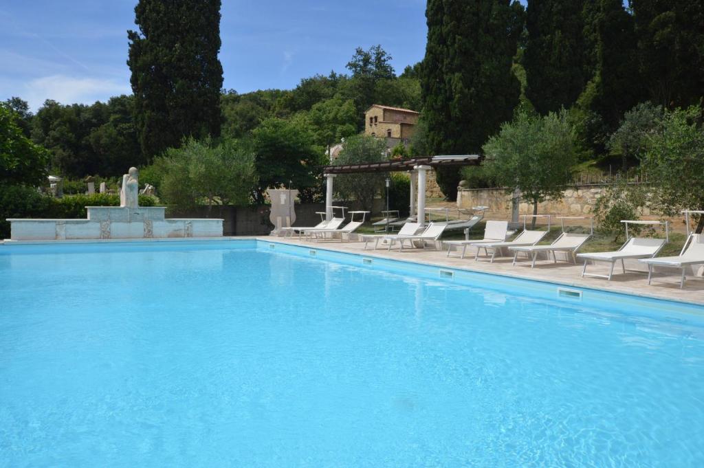 une grande piscine bleue avec des chaises et un bâtiment dans l'établissement Villa Le Querciolaie, à Monteverdi Marittimo