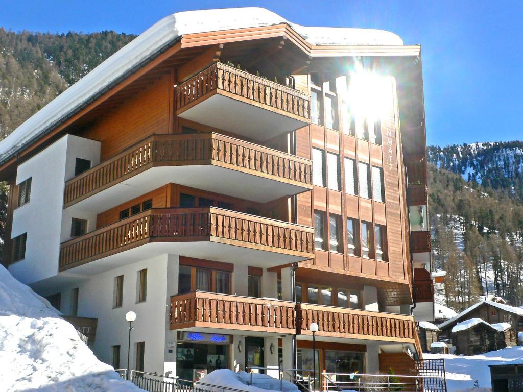 a large building with balconies on it in the snow at Brunnmatt Holiday Apartment Zermatt in Zermatt