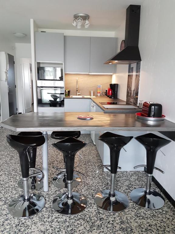 uma cozinha com uma mesa e alguns bancos de bar em Les Cyclades em Le Lavandou