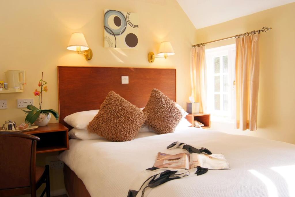 a hotel room with a bed and a window at Tumbling Weir Hotel in Ottery Saint Mary