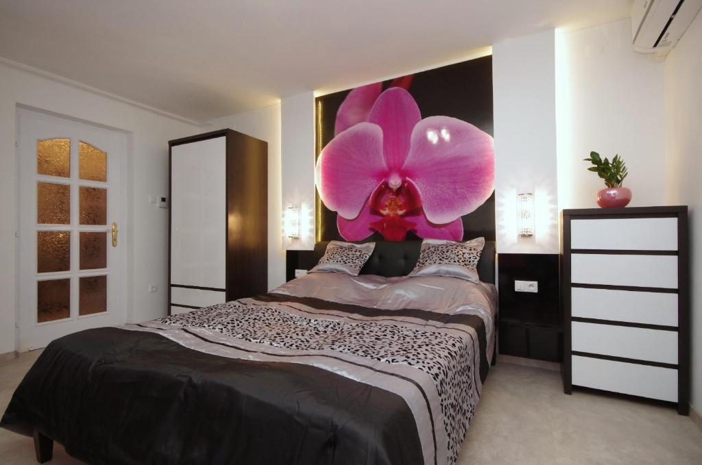 a bedroom with a large pink flower on the wall at Regina Delux Apartman in Gyula