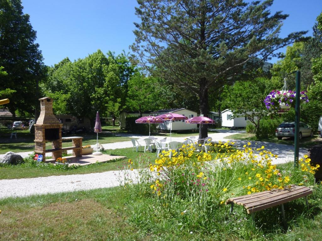 un parque con un banco, mesas y flores en Camping Notre Dame, en Castellane