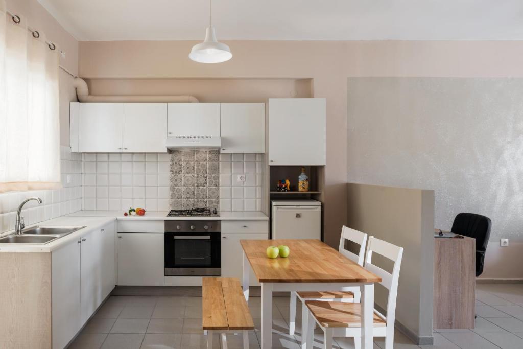 レティムノ・タウンにあるCentral Luxury Apartmentの白いキャビネットと木製テーブル付きのキッチン
