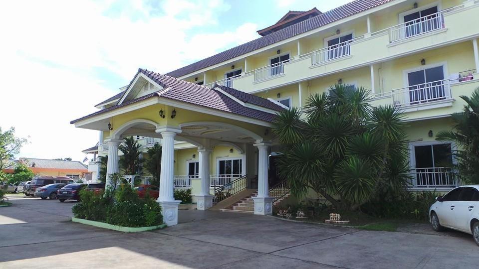 un gran edificio amarillo con un gran porche en Monrawee Pavilion Resort, en Phitsanulok