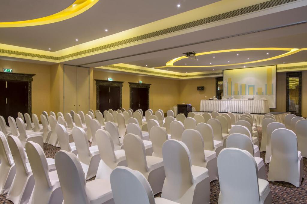 an empty banquet hall with white chairs and tables at Metropolitan Al Mafraq Hotel in Abu Dhabi