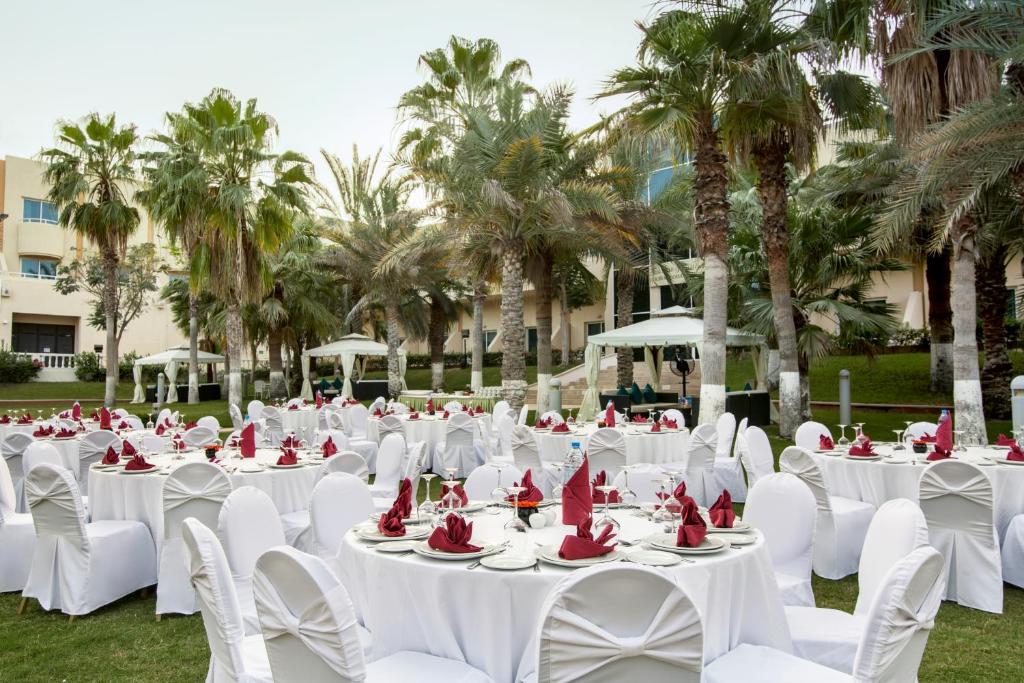 a set of tables with white chairs and red napkins at Metropolitan Al Mafraq Hotel in Abu Dhabi