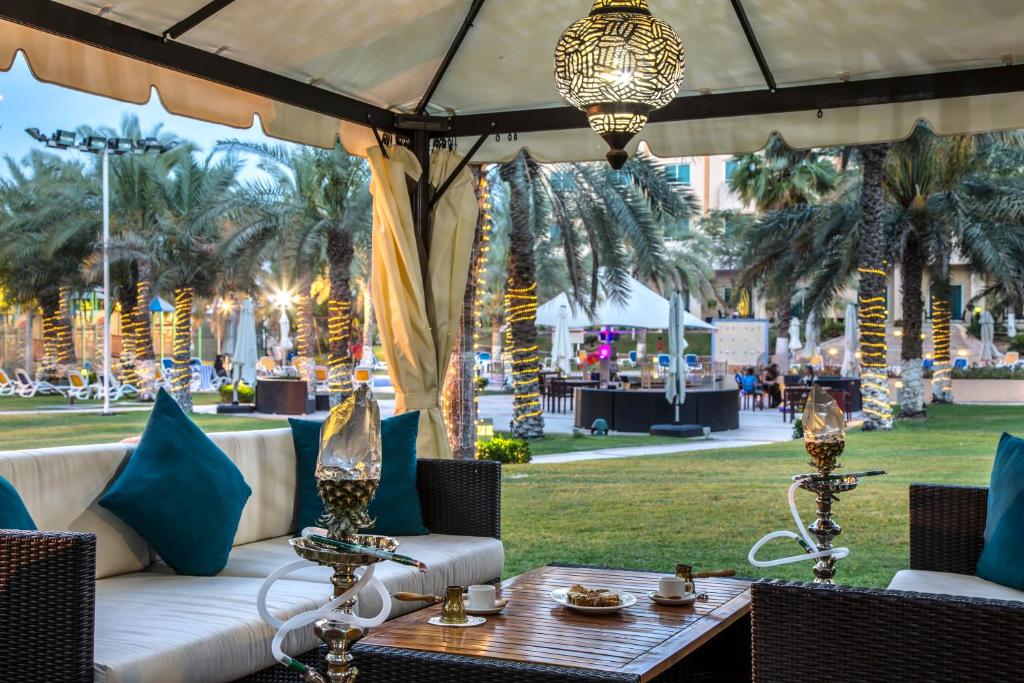 a patio with a white couch and chairs and a table at Metropolitan Al Mafraq Hotel in Abu Dhabi