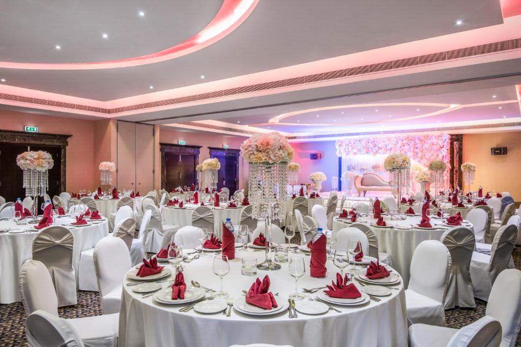 a banquet hall with white tables and white chairs at Metropolitan Al Mafraq Hotel in Abu Dhabi