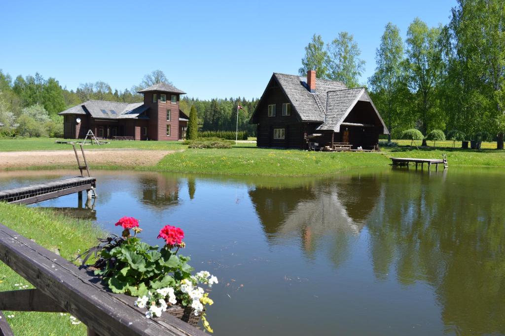 ein Haus und ein Teich mit Blumen auf einem Zaun in der Unterkunft Recreation Center Brūveri in Sigulda